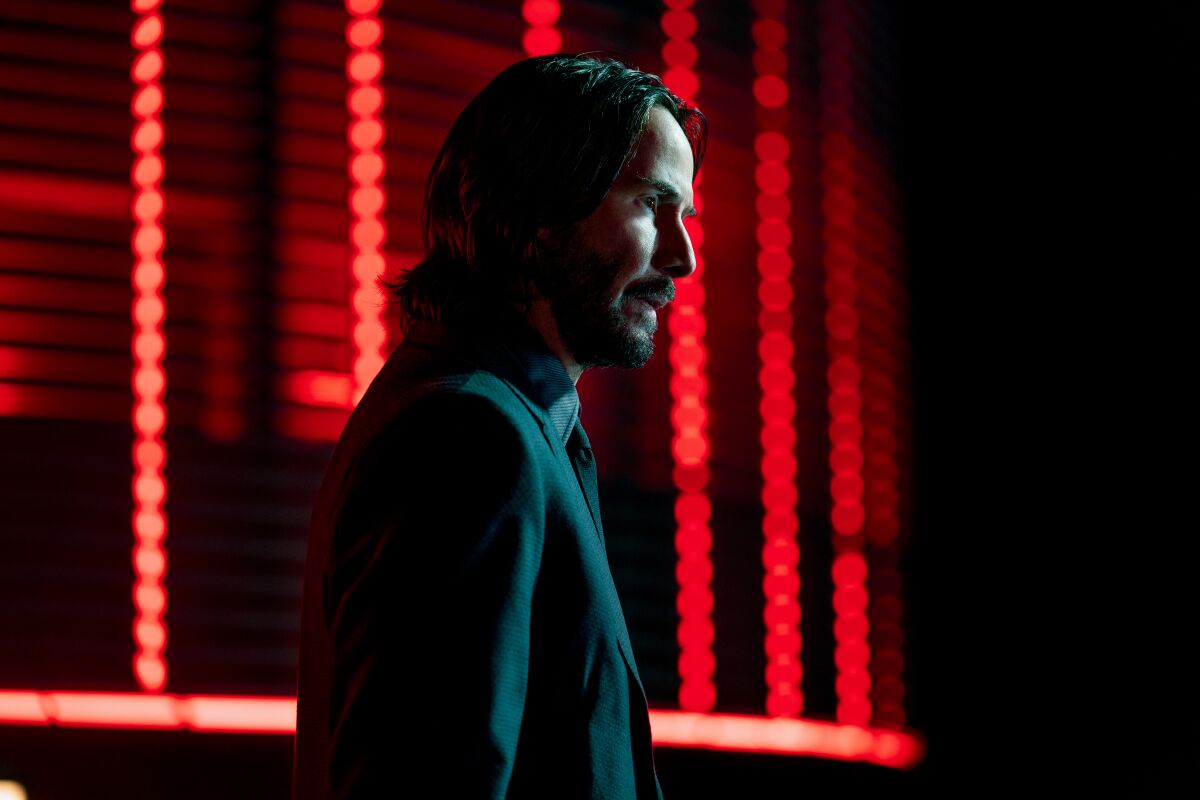 Keanu Reeves silhouetted against red light in a scene 