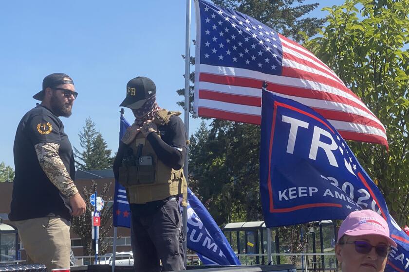 Men wearing symbols of Proud Boys, a right-wing extremist group, stand watch as supporters of President Donald Trump kick off a truck caravan near Portland Monday.