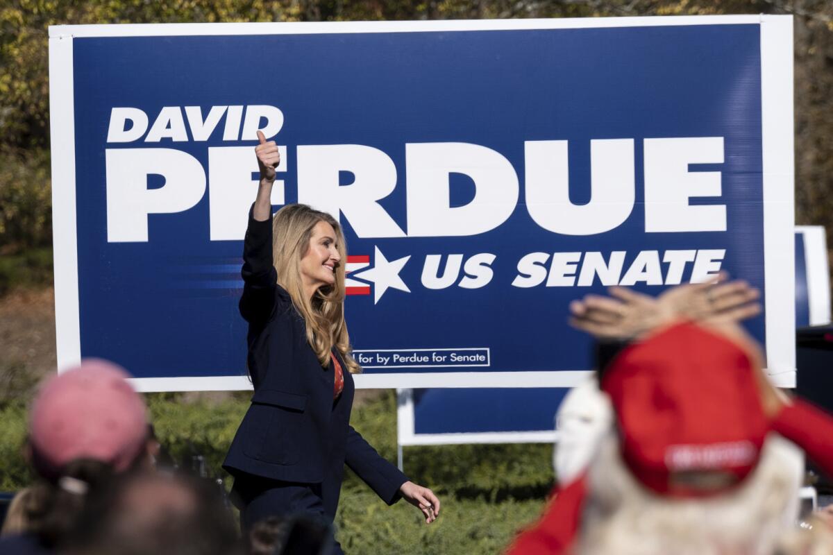 Sen. Kelly Loeffler takes the stage at a rally with a David Purdue for U.S. Senate sign behind her.