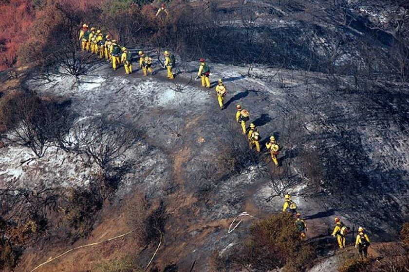 A Cal Fire crew from San Diego walks over a charred area on their way to mop up hot spots in the area southeast of Highway 39.
