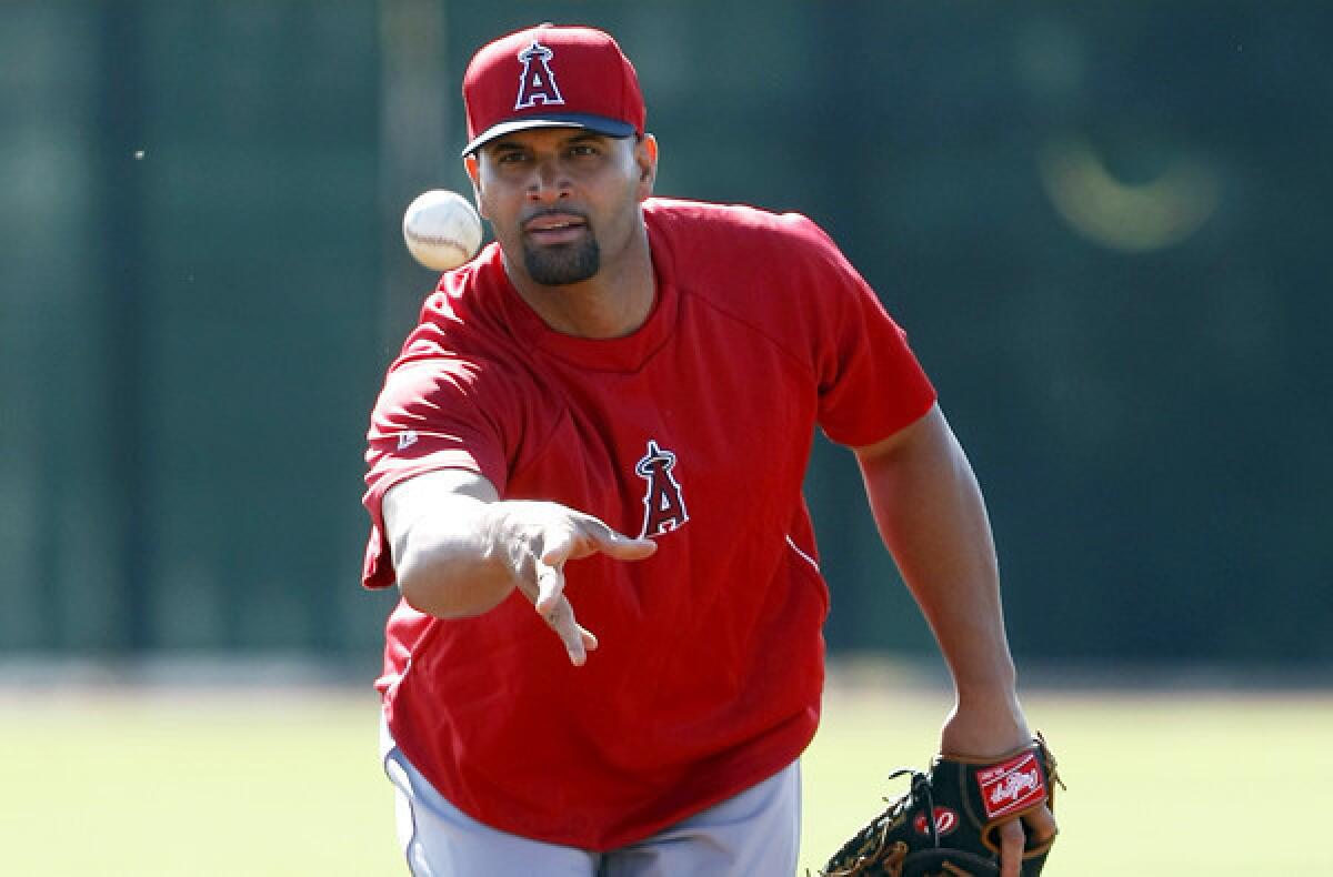 Angels first baseman Albert Pujols tosses the ball to first base during a spring training workout Thursday in Tempe, Ariz.
