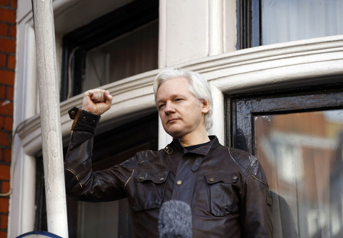 Julian Assange raises his fist in the air