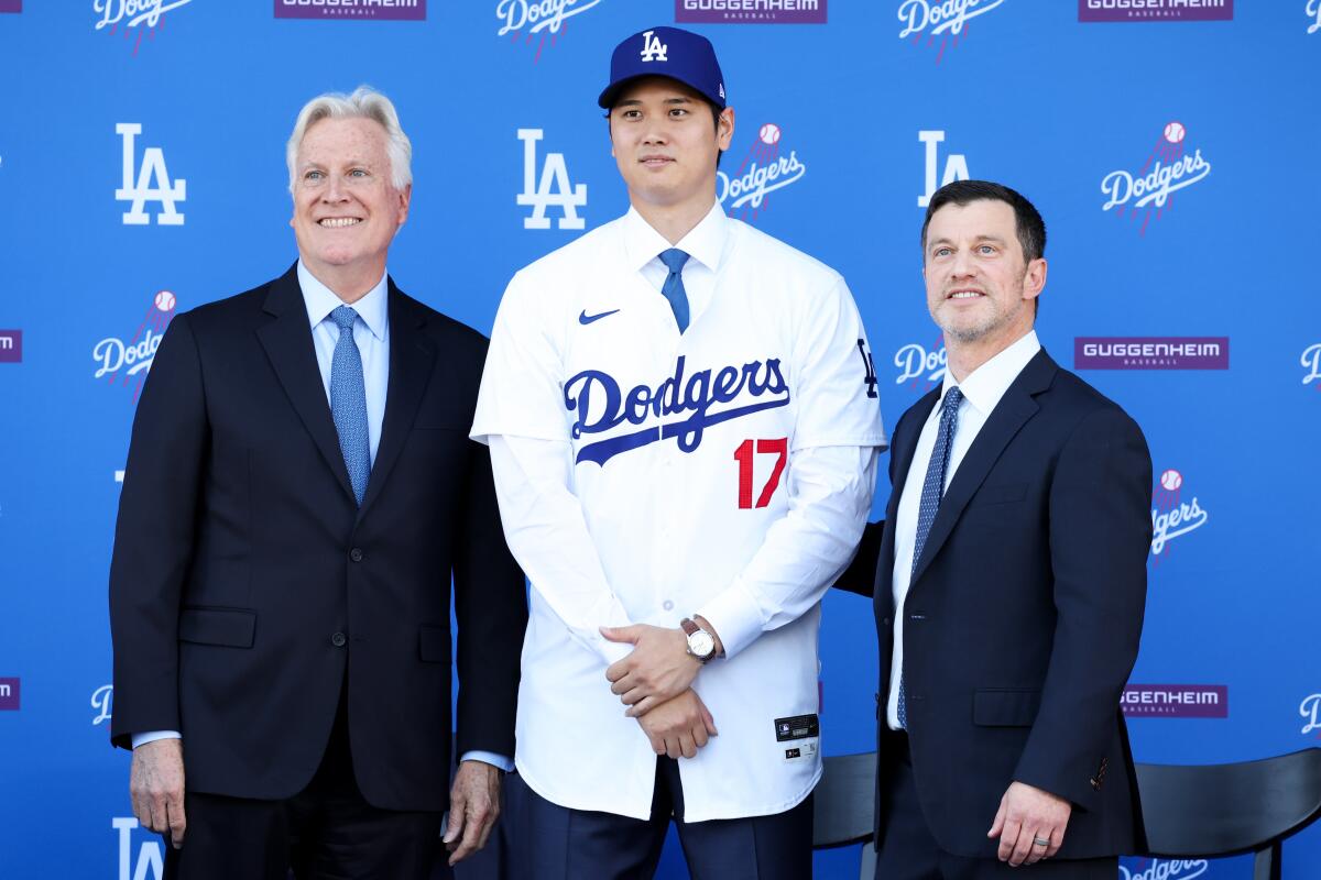 Shohei Ohtani pose avec Mark Walter, à gauche, et Andrew Friedman, à droite, le 14 décembre 2023, au Dodger Stadium.