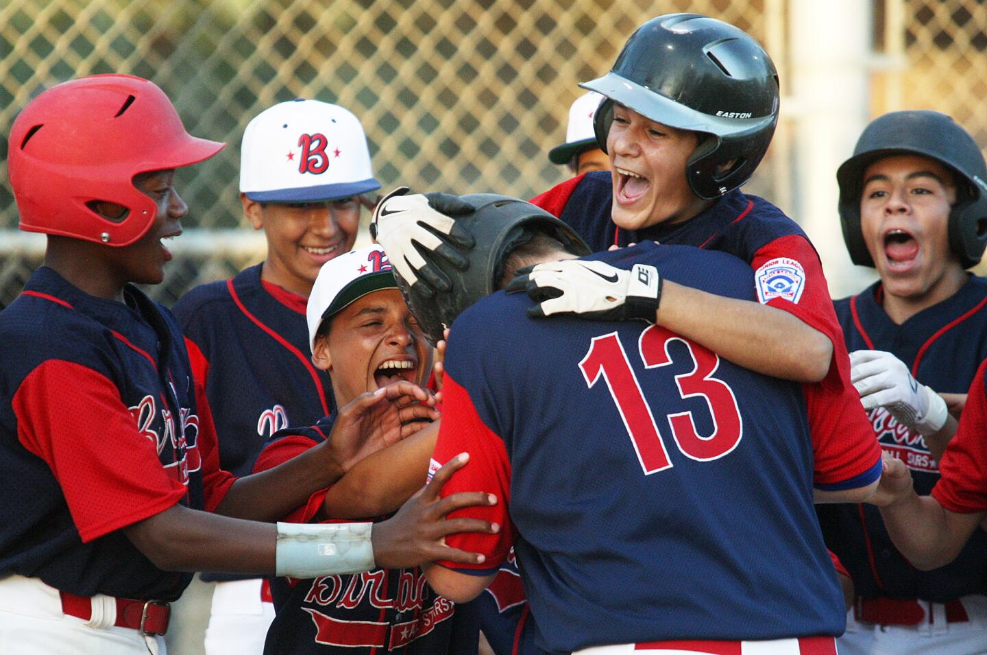Burbank's Scott Breslin (13) is exhuberantly congratulated at homeplate after hitting a two-run homerun against Crescenta Valley in a Little League Junior Baseball all-star game at Scholl Canyon Fields on Monday, July 7, 2014.
