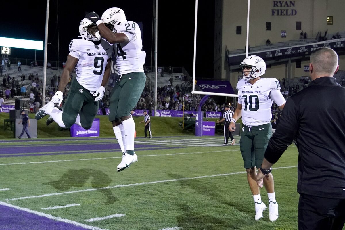 Michigan State running back Kenneth Walker III (9) celebrates with running back Elijah Collins (24) after Walker scored a touchdown during the first half against Northwestern in an NCAA college football game in Evanston, Ill., Friday, Sept. 3, 2021. At right is quarterback Payton Thorne. (AP Photo/Nam Y. Huh)