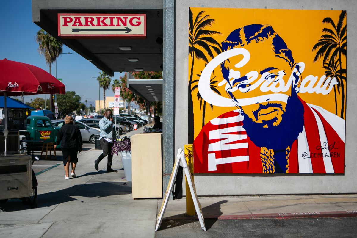 A poster of Nipsey Hussle on a wall with the word "Crenshaw" across his face