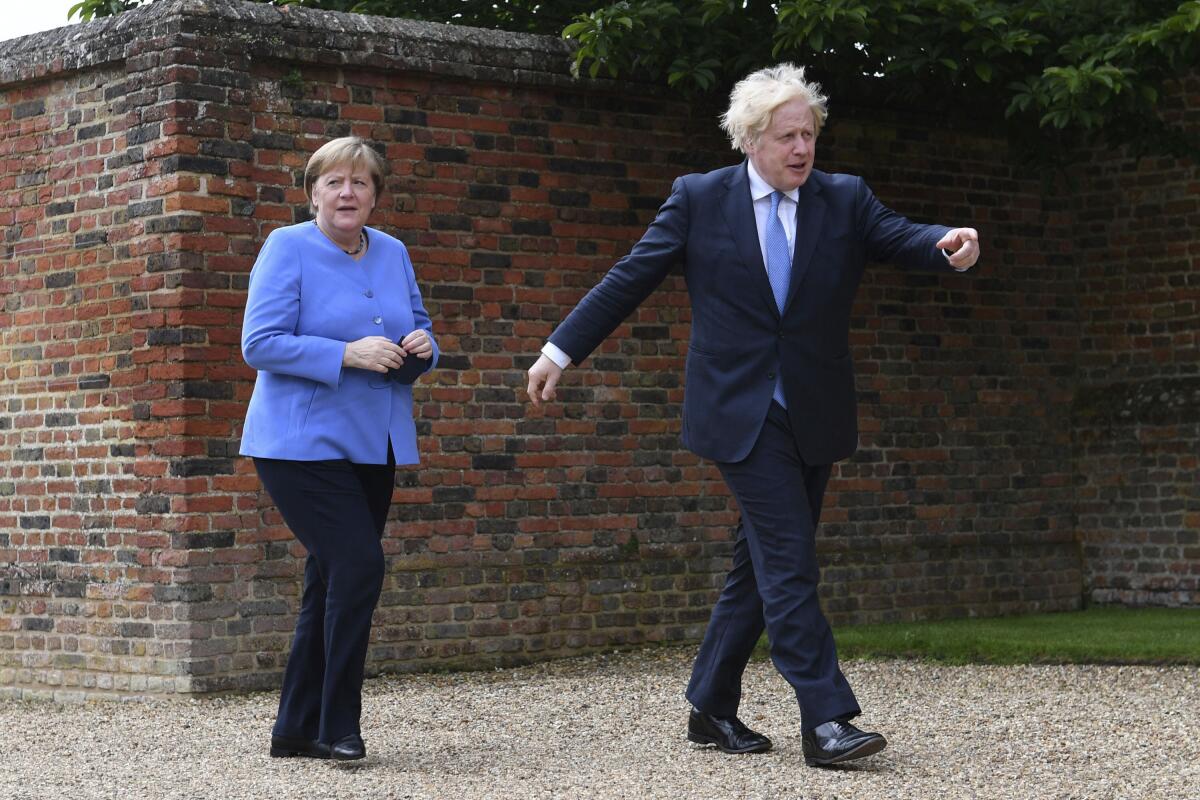 Britain's Prime Minister Boris Johnson, right, welcomes German Chancellor Angela Merkel, before their bilateral meeting at Chequers, the country house of the Prime Minister, in Buckinghamshire, England, Friday July 2, 2021. Johnson is likely to push Angela Merkel to drop her efforts to impose COVID-19 restrictions on British travelers as the German chancellor makes her final visit to Britain before stepping down in the coming months. Johnson will hold talks with Merkel at his country residence on Friday. (Stefan Rousseau/Pool Photo via AP)