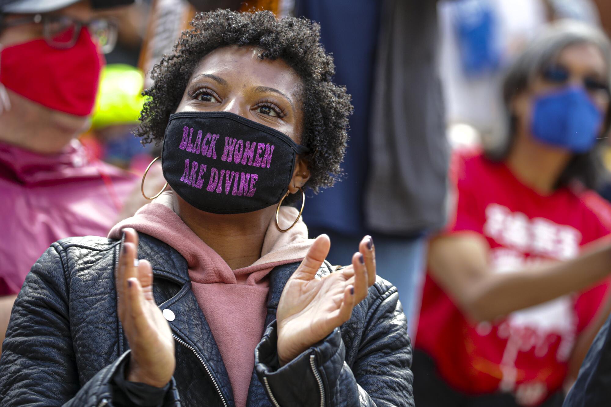 A person wears a mask that says, "Black women are divine." 