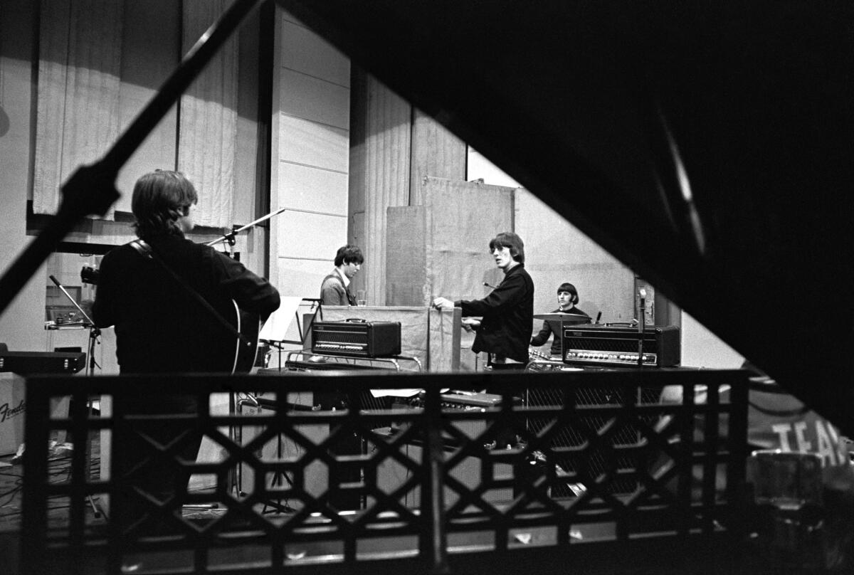 A black-and-white photo of a rock band in the recording studio in the 1960s