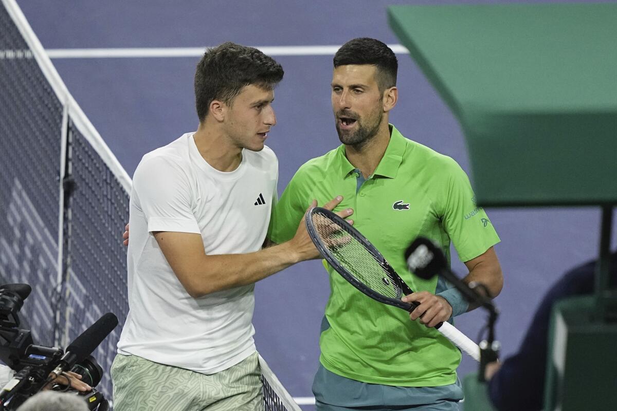 Luca Nardi, of Italy, talks with Novak Djokovic, of Serbia, after upsetting Djokovic.