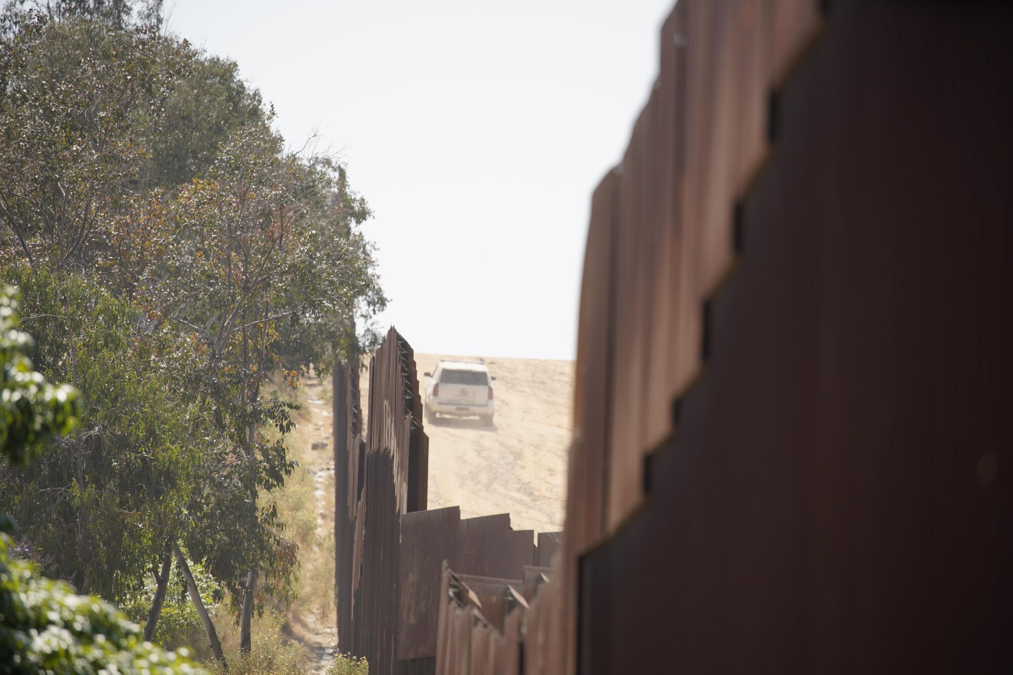 The view from Colonia Soler in Tijuana, where a Border Patrol vehicle drives along the U.S. side of the border fence.
