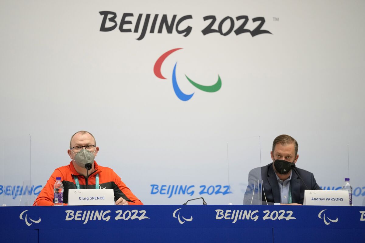 International Paralympic Committee President Andrew Parsons, right, and spokesman Craig Spence listen to a question from a member of the media during a press conference at the 2022 Winter Paralympics, Thursday, March 3, 2022, in Beijing. In a stunning reversal, Russian and Belarusian athletes have been banned from the Winter Paralympic Games for their countries' roles in the war in Ukraine, the International Paralympic Committee said Thursday in Beijing. (AP Photo/Dita Alangkara)