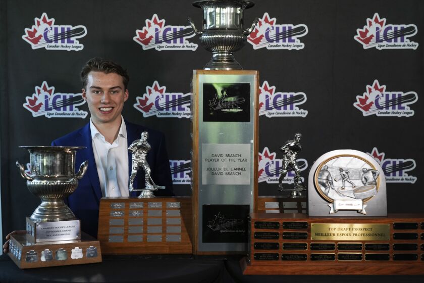 Regina Pats center Connor Bedard poses for photographs with the trophies he received at the Canadian Hockey League awards ceremony in Kamloops, British Columbia, Saturday, June 3, 2023. Bedard won the CHL Top Prospect, Top Scorer, and David Branch Player of the Year awards. It's the first time since the Top Scorer award was introduced in 1994 that a player has won all three in a single season. (Darryl Dyck/The Canadian Press via AP)