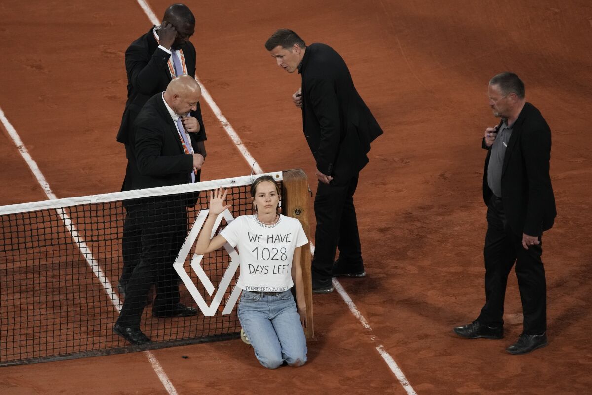 A climate activist tied herself to the net during the semifinal match between Croatia's Marin Cilic and Norway's Casper Ruud at the French Open tennis tournament in Roland Garros stadium in Paris, France, Friday, June 3, 2022. (AP Photo/Christophe Ena)