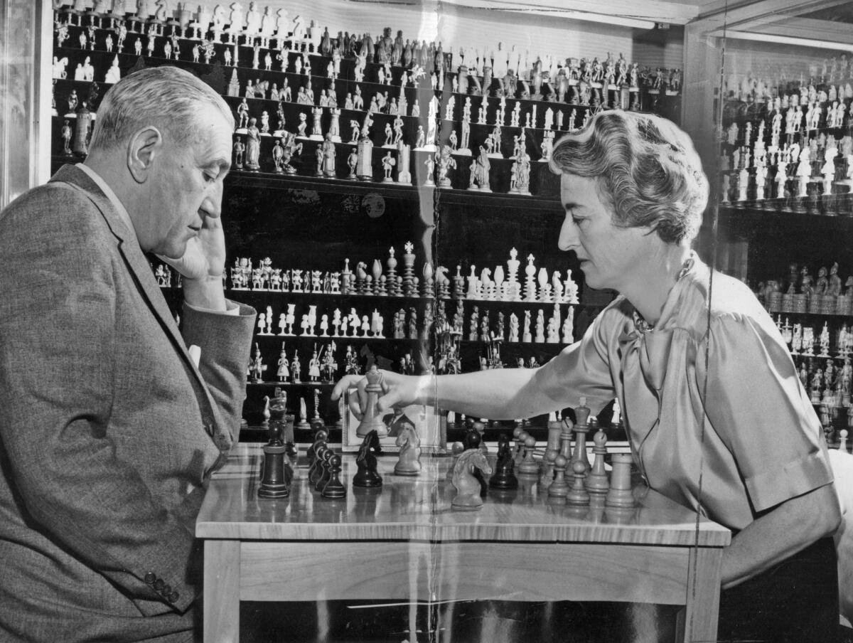 A photo from 1962 shows Gregor, left, and Jacqueline Piatigorsky playing chess in front of their chess collection. Jacqueline was a champion player.