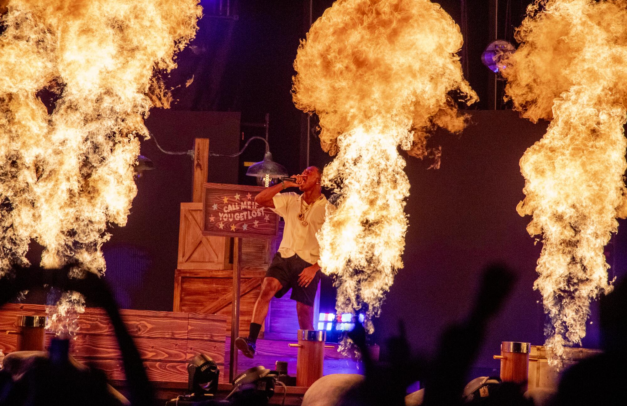 A man performing onstage with balls of fire on the edge of the stage 