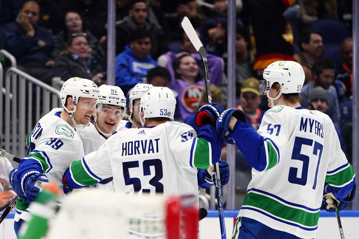 Vancouver Canucks' Vasily Podkolzin (92) celebrates with teammates Oliver Ekman-Larsson (23), Alex Chiasson (39), Bo Horvat (53) and Tyler Myers (57) after scoring a goal during the third period of an NHL hockey game against the New York Islanders, Thursday, March 3, 2022, in Elmont, N.Y. (AP Photo/Frank Franklin II)