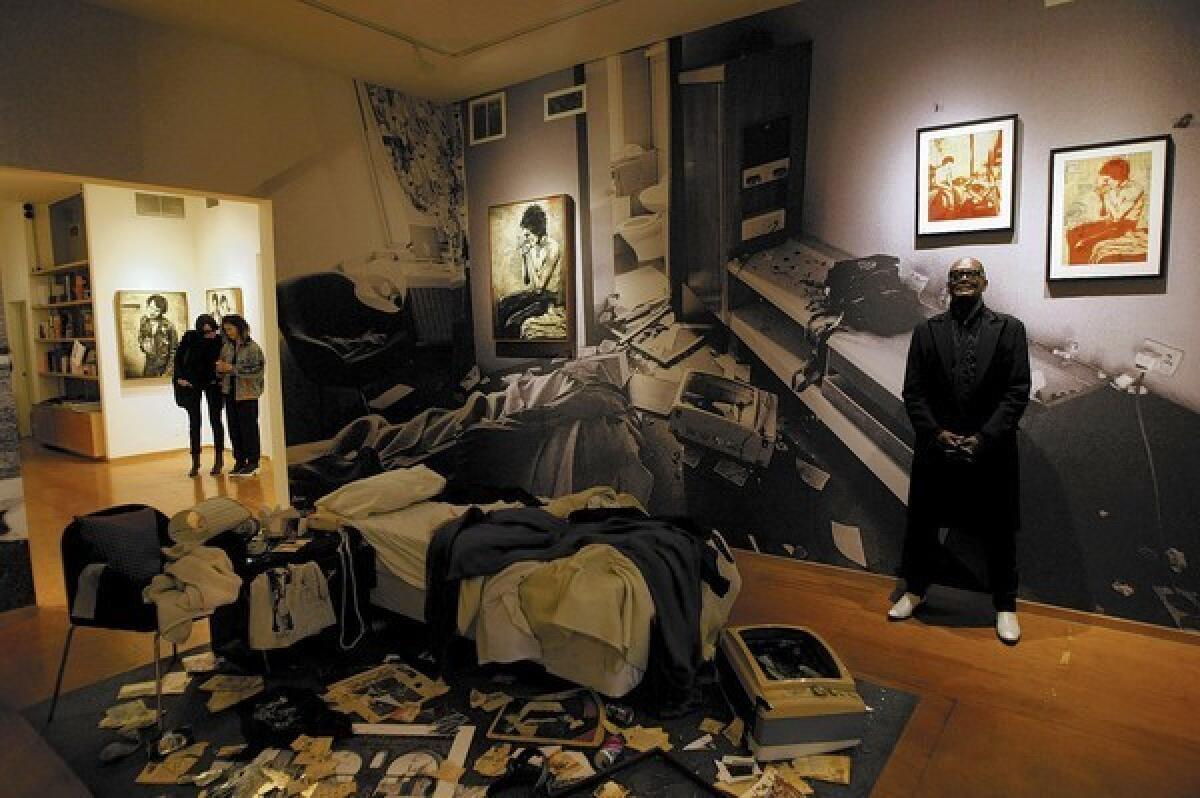 Longtime Sex Pistols photographer Dennis Morris stands in a re-creation of a Chelsea Hotel room trashed by Sid Vicious that is part of a new collection of art and photos inspired by Vicious, from street art maven Shepherd Fairey and Morris titled "Sid — Superman is Dead," at Subliminal Projects gallery in Los Angeles.