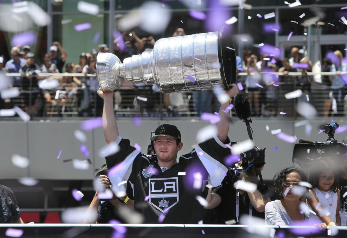 Kings goalie Jonathan Quick raises the Stanley Cup Trophy over his head while confetti pours down on the Kings' victory parade in front of the Staples Center on June 16, 2014.