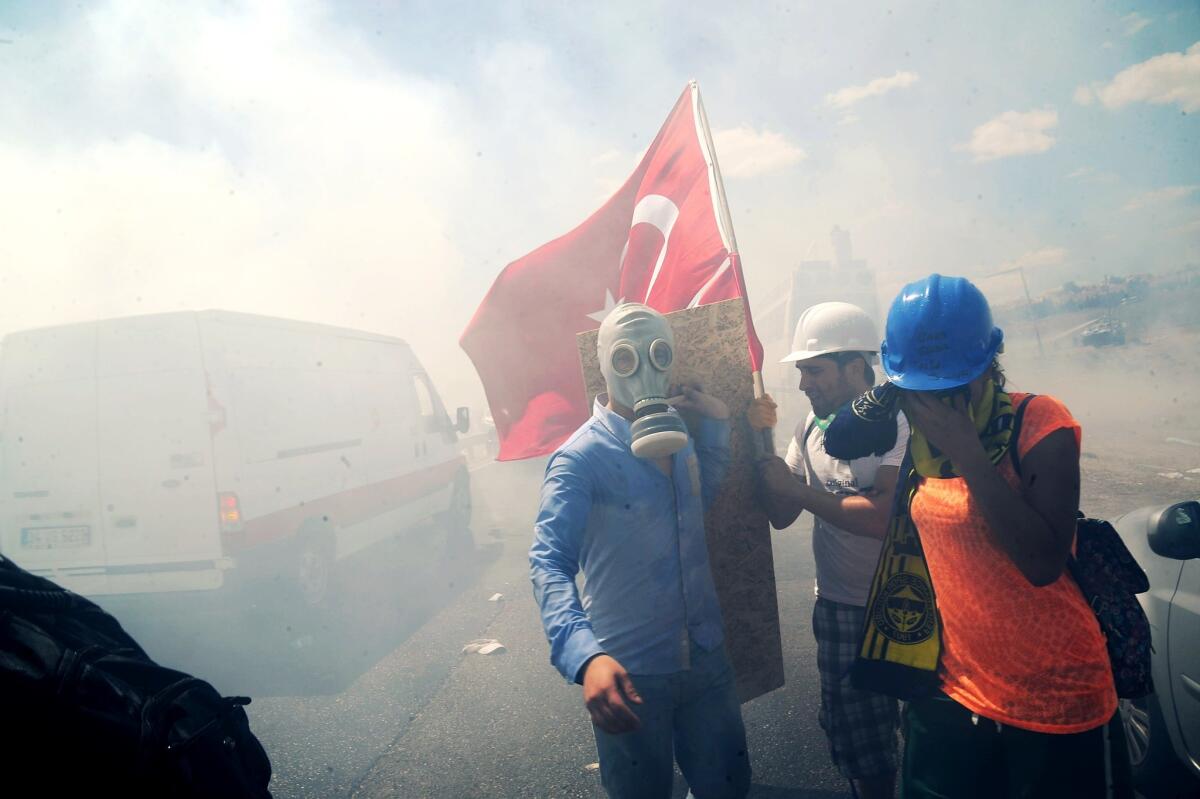 Demonstrators take cover from tear gas during clashes against Turkish police forces near a courthouse in Silivri, near Istanbul, on Monday, after a court decision to sentence a former army chief and other top brass to life in prison in a high-profile trial of 275 people accused of plotting to overthrow the Islamic-rooted government.