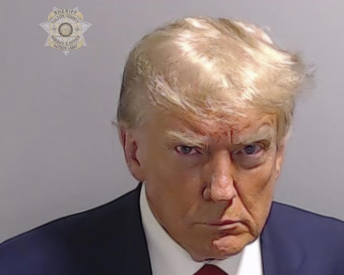 A badly-lit mug shot shows former President Donald Trump scowling into a camera.