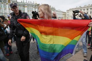 FILE - A police officer speaks with a gay rights activist standing with a rainbow flag, in front of journalists, during a protesting picket at Dvortsovaya (Palace) Square in St. Petersburg, Russia, Aug. 2, 2015. Russian President Vladimir Putin signed new legislation Monday July 24, 2023, that marked the final step in outlawing gender-affirming procedures, a crippling blow to Russia's already embattled LGBTQ+ community. (AP Photo/Dmitry Lovetsky, File)