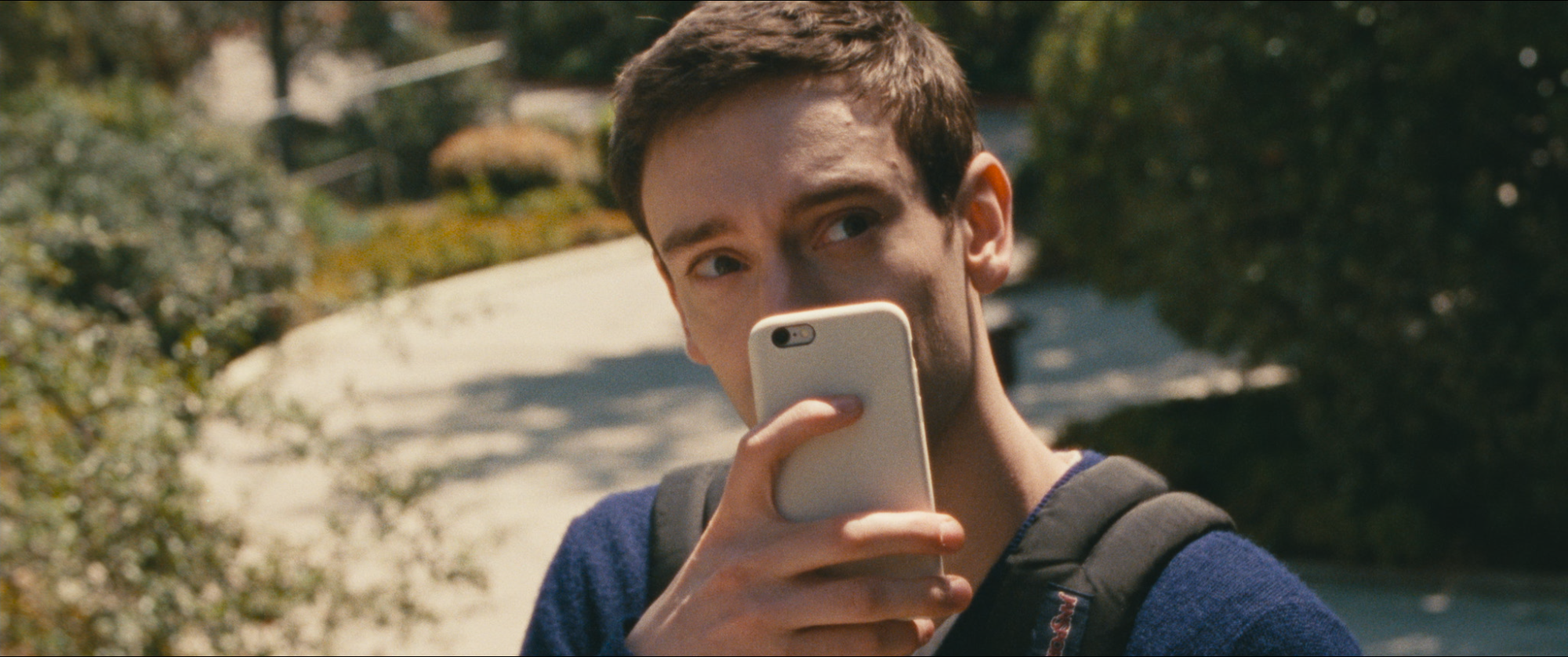 A suspicious man takes a video with a cell in a white case.
