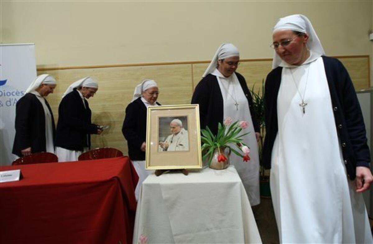 Sister Marie Simon-Pierre, right, and nuns of the Catholic Maternity, pose with a portrait of Pope John Paul II, during a press conference at Aix-en-Provence's archbishopric, Monday, Jan. 17, 2011. The pope has approved a miracle attributed to Pope John Paul II's intercession and set May 1 as the date for the beloved pontiff to be beatified. Pope Benedict XVI declared in a decree Friday, Jan. 14, 2011, that the cure of a French nun, sister Marie Simon-Pierre, who suffered from Parkinson's disease was miraculous, the last step needed for the beatification, in Monday, Jan. 17, 2011. (AP Photo/Claude Paris)