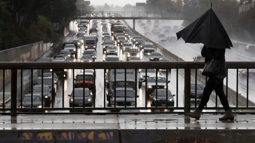 Nayer Shahram walks under a broken umbrella on Louise Avenue in Encino as traffic crawls along the 101 Freeway during a storm in early December.