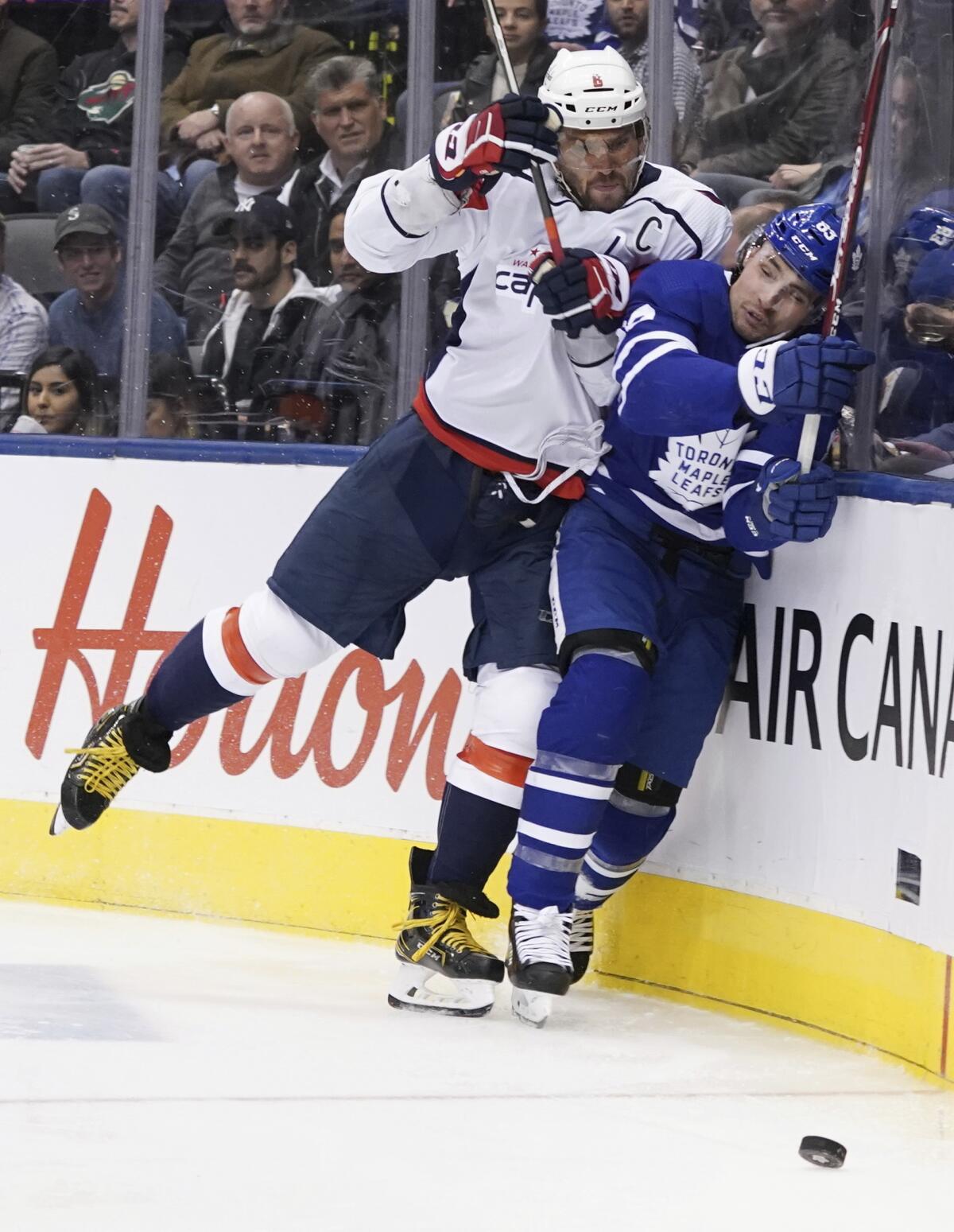 Capitals left wing Alex Ovechkin (8) checks Maple Leafs defenseman Cody Ceci (83) into the boards during a game at Scotiabank Arena.