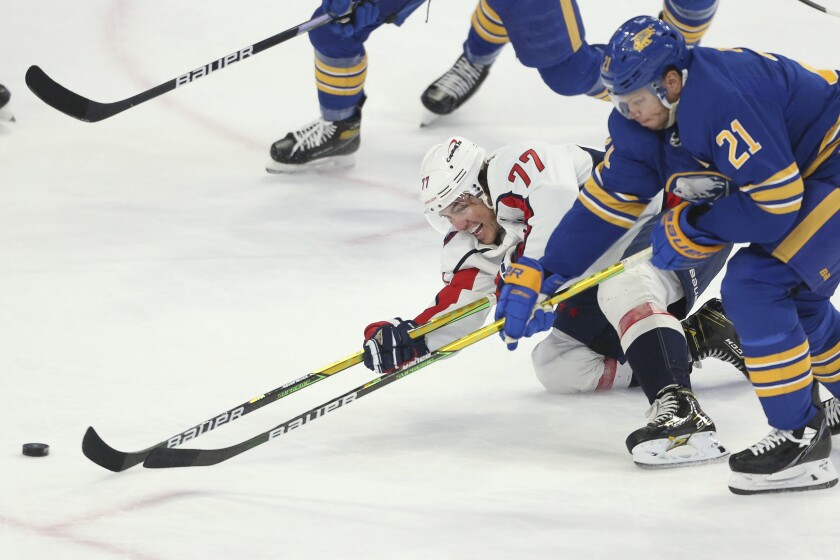 Washington Capitals right wing T.J. Oshie (77) and Buffalo Sabres right wing Kyle Okposo (21) compete for possession of the puck during the third period of an NHL hockey game Saturday, Dec. 11, 2021, in Buffalo, N.Y. (AP Photo/Joshua Bessex)