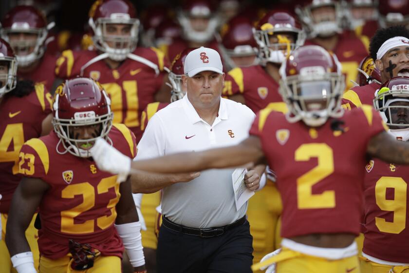 Southern California coach Clay Helton, center, runs onto the field with his team for an NCAA college football game against Utah on Friday, Sept. 20, 2019, in Los Angeles. (AP Photo/Marcio Jose Sanchez)