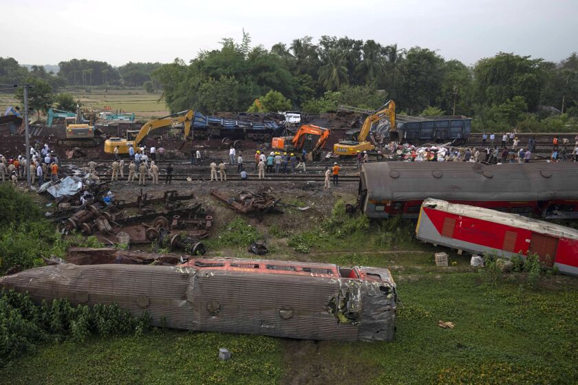 Gente mirando en el lugar donde descarrilaron varios trenes en el distrito de Balasore, en el estado oriental indio de Orissa, el domingo 4 de junio de 2023. (AP Foto/Rafiq Maqbool)
