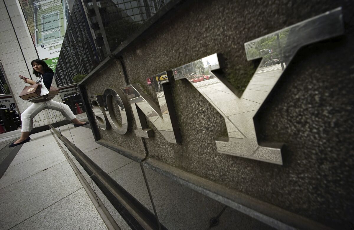 FILE - In this April 30, 2015, file photo, a woman sits near the logo of Sony Corp. in Tokyo. Japanese electronics and entertainment company Sony Corp. said Tuesday that its April-June profit jumped 53% as its video-game and other online businesses thrived with people staying home due to the coronavirus pandemic. (AP Photo/Eugene Hoshiko, File)