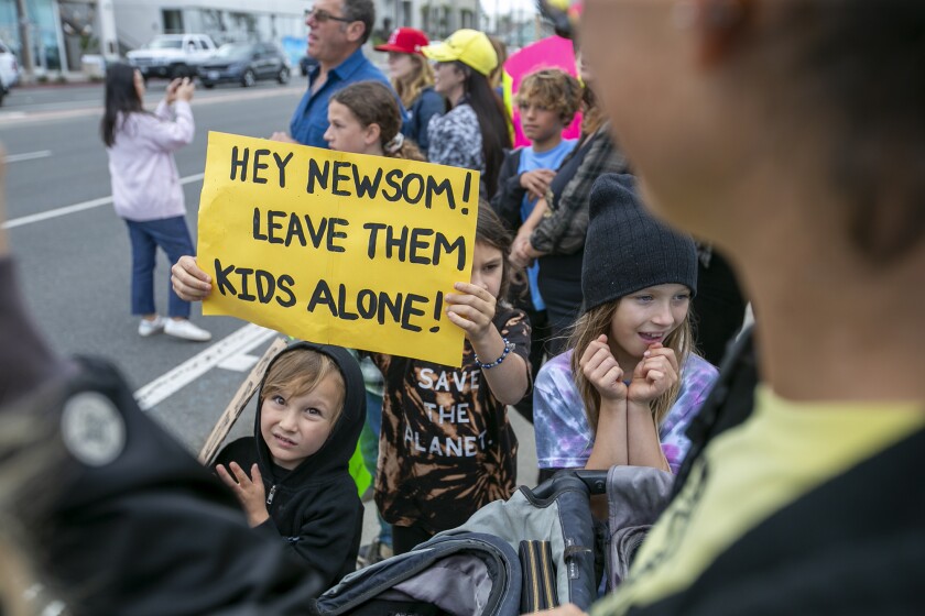 A student holds a sign with a message for Gov. Gavin Newsom during a school walk-out to oppose vaccination mandates Monday.