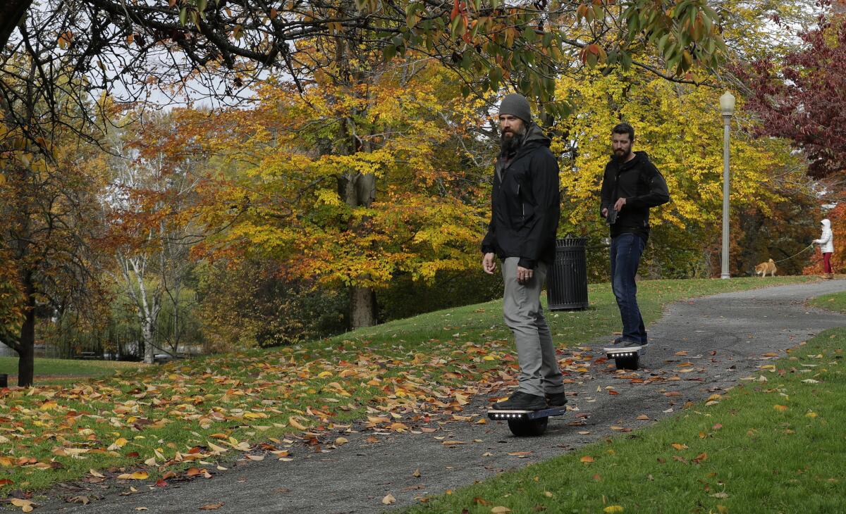 Two people ride Onewheel electric skateboards 