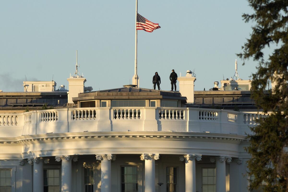 Members of the US Secret Service stand atop the White House, where the US national flag flies at half staff to honor the victims of the San Bernardino mass shooting on December 3.