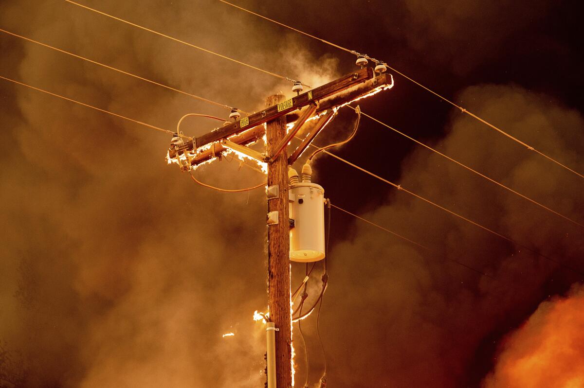 Fire burns along a power pole at night 