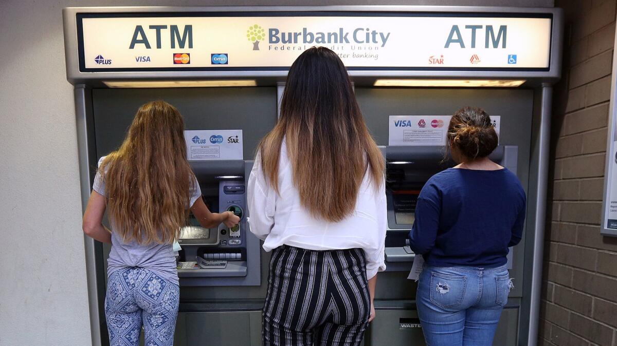 An adviser works with two students to show them how to transfer $20 at the Burbank City Federal Credit Union.