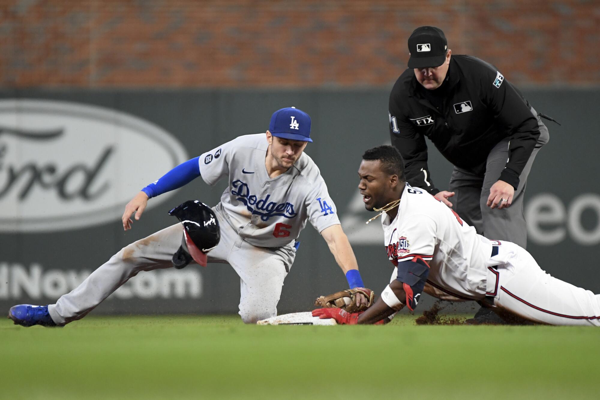 Braves' Jorge Soler dives into second base on a double ahead of the tag by Dodgers second baseman Trea Turner