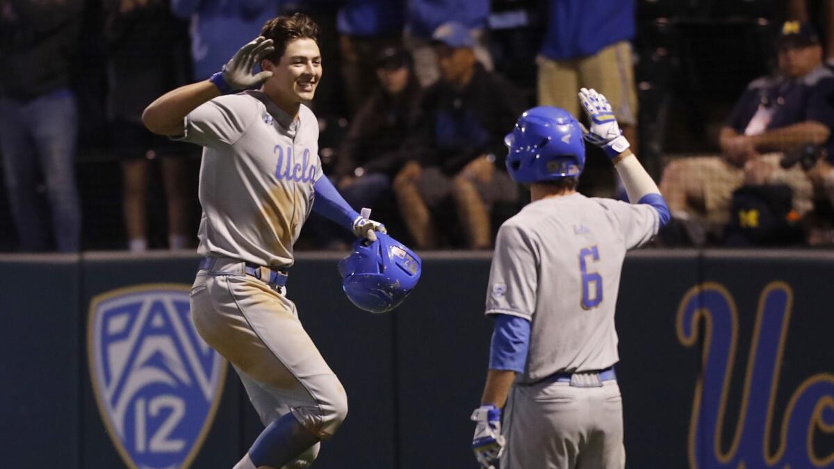 UCLA's Michael Toglia, left, is congratulated by teammate Jack Stronach after hitting a solo home run during the eighth inning of a 5-4 victory in 12 innings over Michigan in an NCAA super regional on June 8.