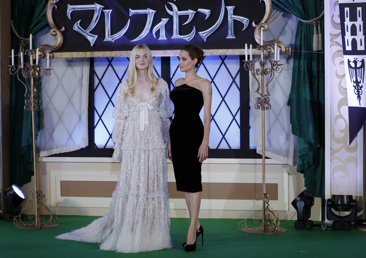 Angelina Jolie wore a sexy black cocktail dress by Atelier Versace and Elle Fanning was in a frothy white Alexander McQueen at the Japan premiere of "Maleficent" in Tokyo on Monday.