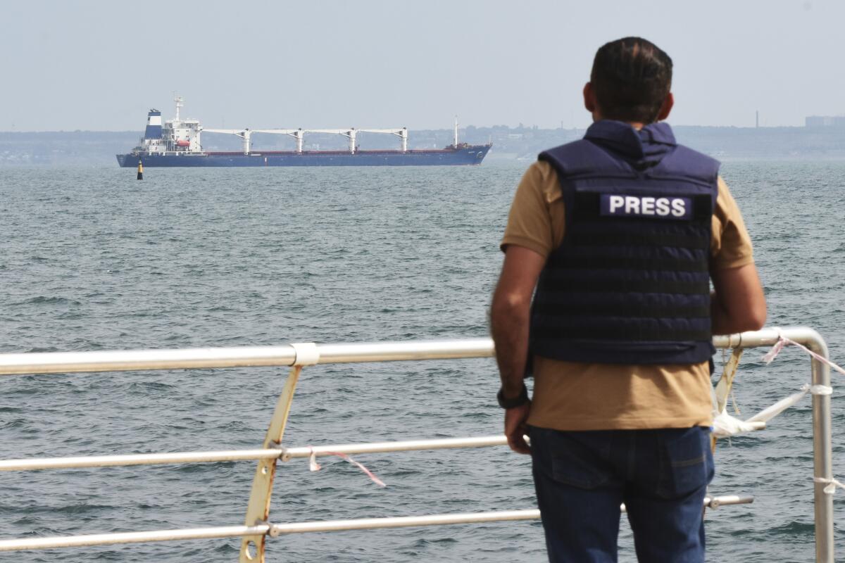 Journalist watching cargo ship exiting port