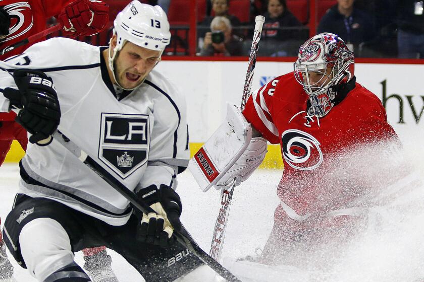 Kings forward Kyle Clifford, left, can't keep control of the puck in front of Carolina Hurricanes goalie Cam Ward during the first period of the Kings' 3-2 loss Sunday.