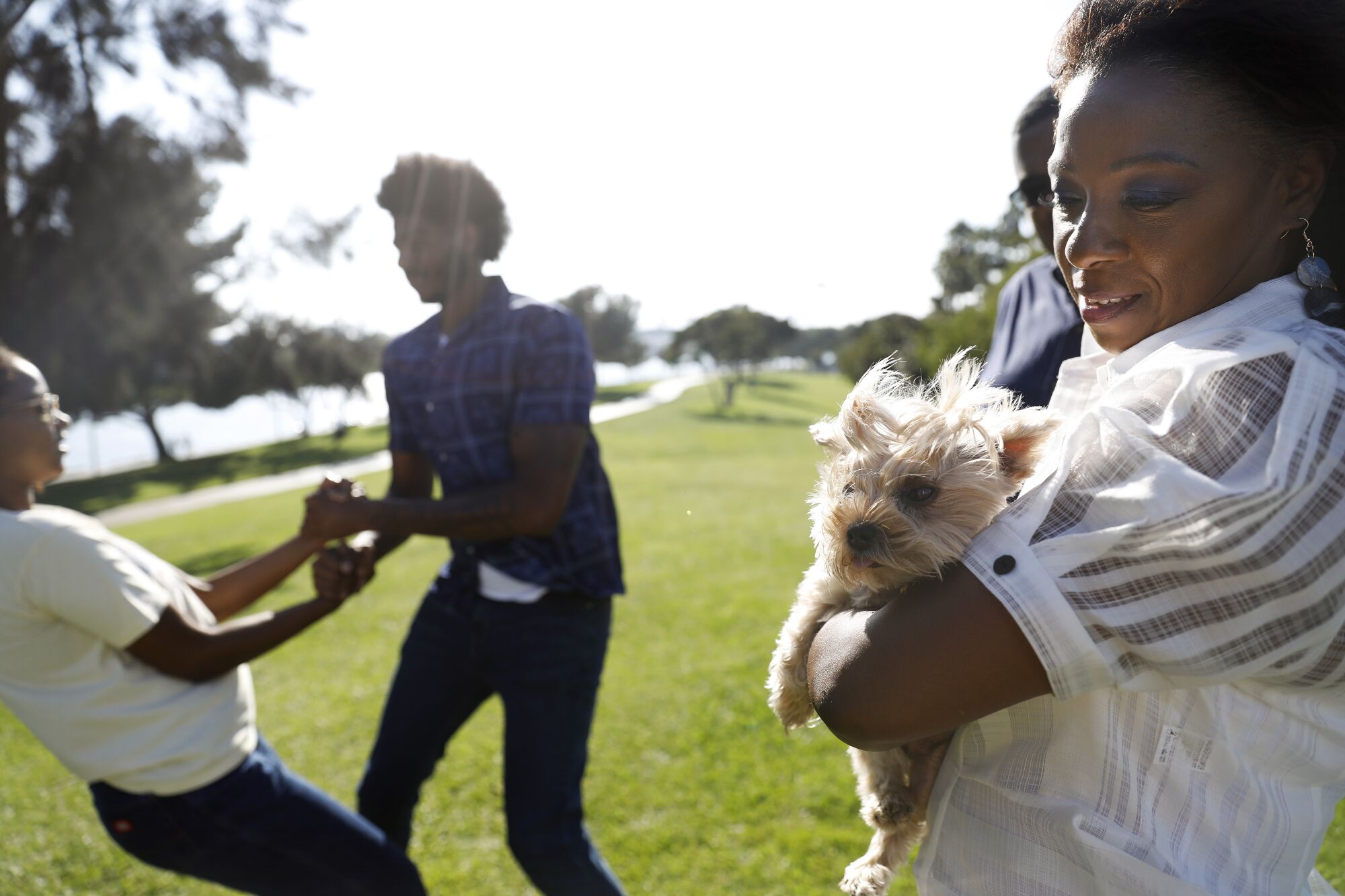 Myles Johnson plays with his sister Riley, 17, left, and their mom Gigi, right, holds the family dog Truffles