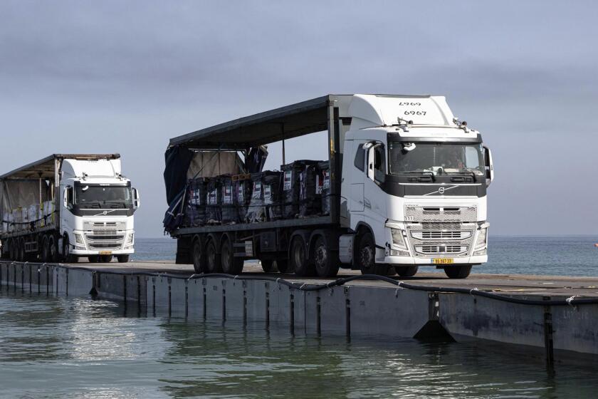 This image provided by the U.S. Army shows trucks loaded with humanitarian aid from the United Arab Emirates and the United States Agency for International Development cross the Trident Pier before arriving on the beach on the Gaza Strip Friday, May 17, 2024. Trucks carrying badly needed aid for the Gaza Strip rolled across a newly built U.S. pier and into the besieged enclave for the first time Friday as Israeli restrictions on border crossings and heavy fighting hindered the delivery of food and other supplies. (Staff Sgt. Malcolm Cohens-Ashley/U.S. Army via AP)