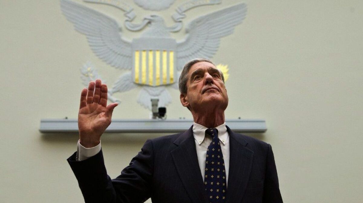 Robert S. Mueller III raises his right hand to take an oath in 2013.