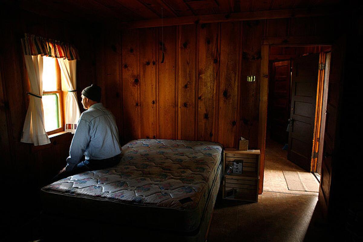 George Harper sits on the edge of his bed before taking down the curtains in his cottage.