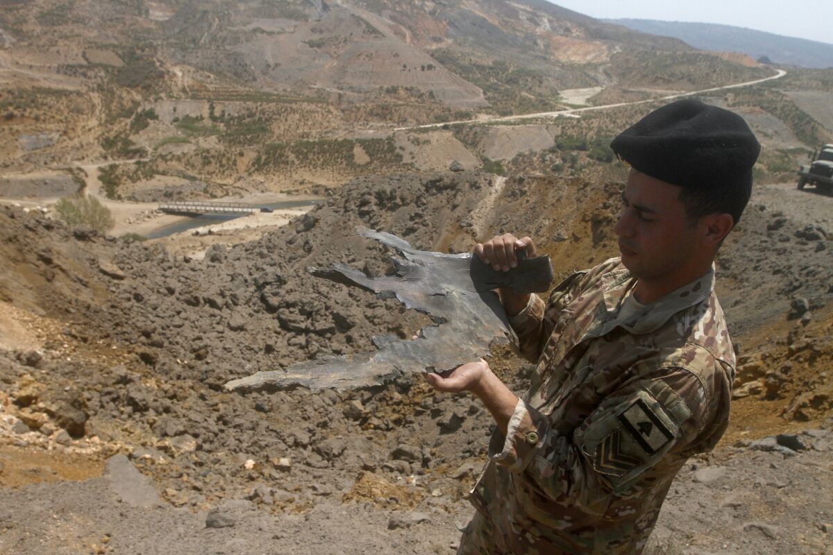 A Lebanese army soldier displays part of an Israeli missile from an airstrike in Dimashqiya farmlands, southern Lebanon, Thursday, Aug 5, 2021. Israel on Thursday escalated its response to rocket attacks this week by launching rare airstrikes on Lebanon, the army and Lebanese officials said. (AP Photo/Mohammed Zaatari)
