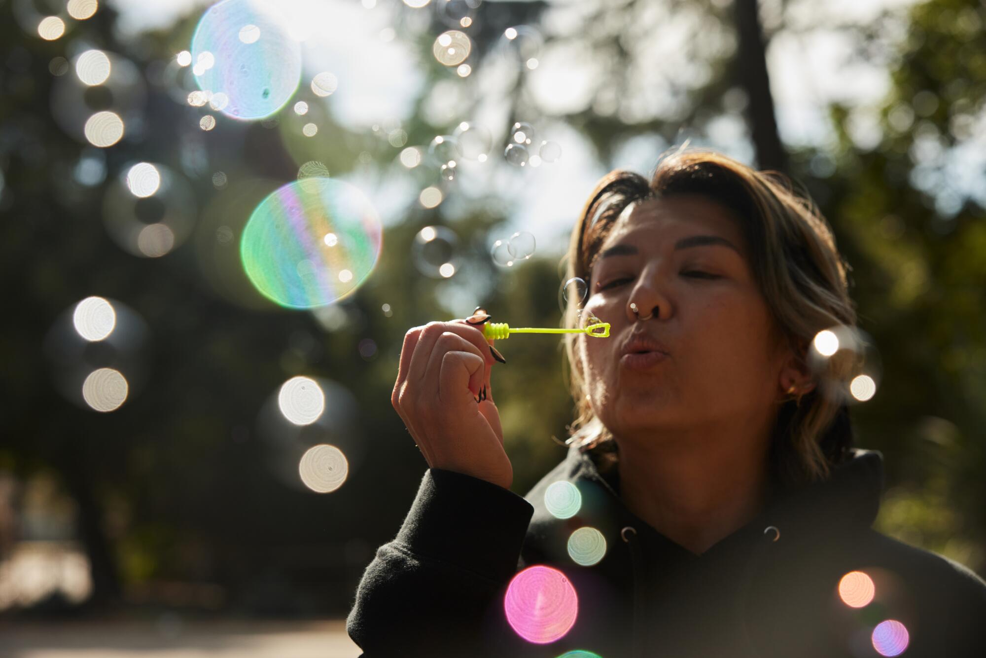 A woman blows bubbles through a bubble wand at the Huntington.